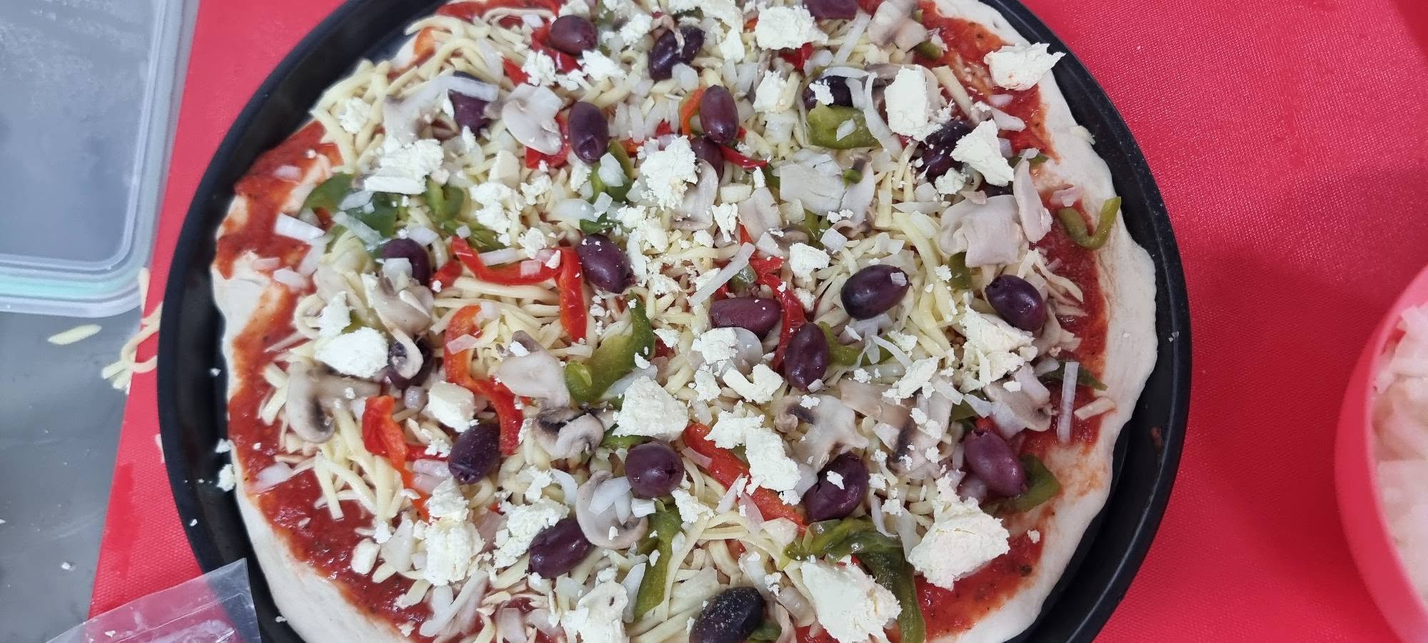 A Veggie Delight pizza being topped fresh to order